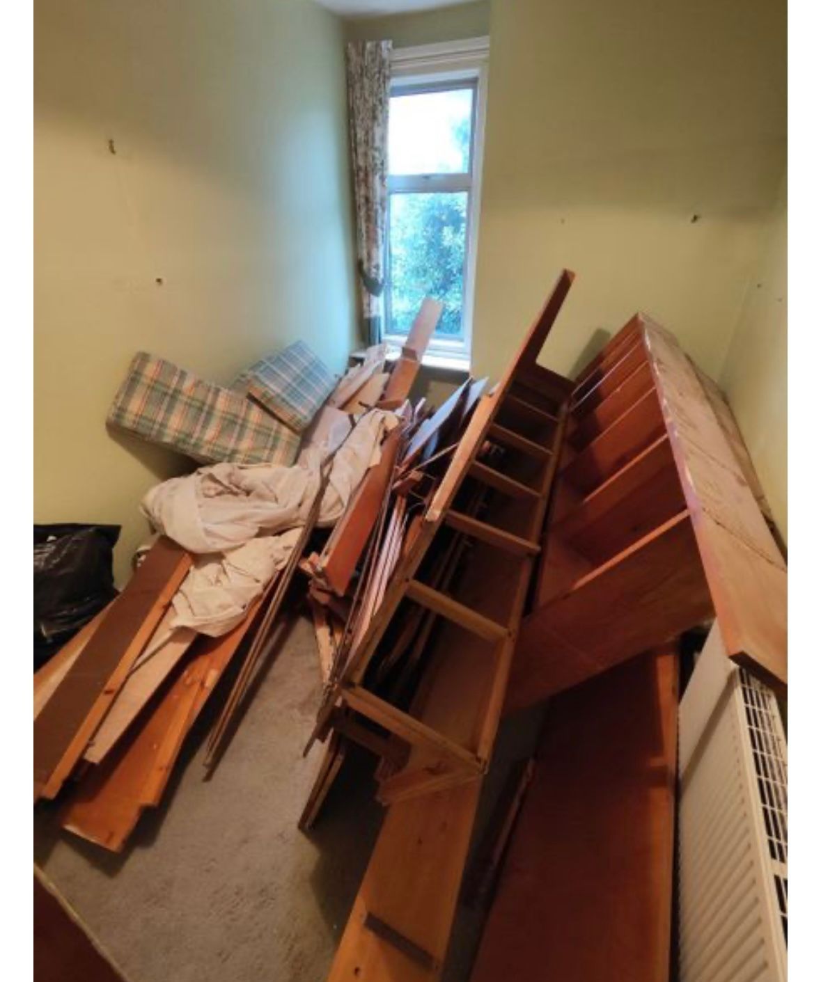 Wooden chairs and a headboard stacked in a room for collection.