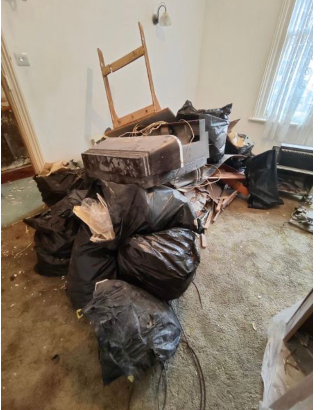 Bagged household waste stacked in a room during a clearance.