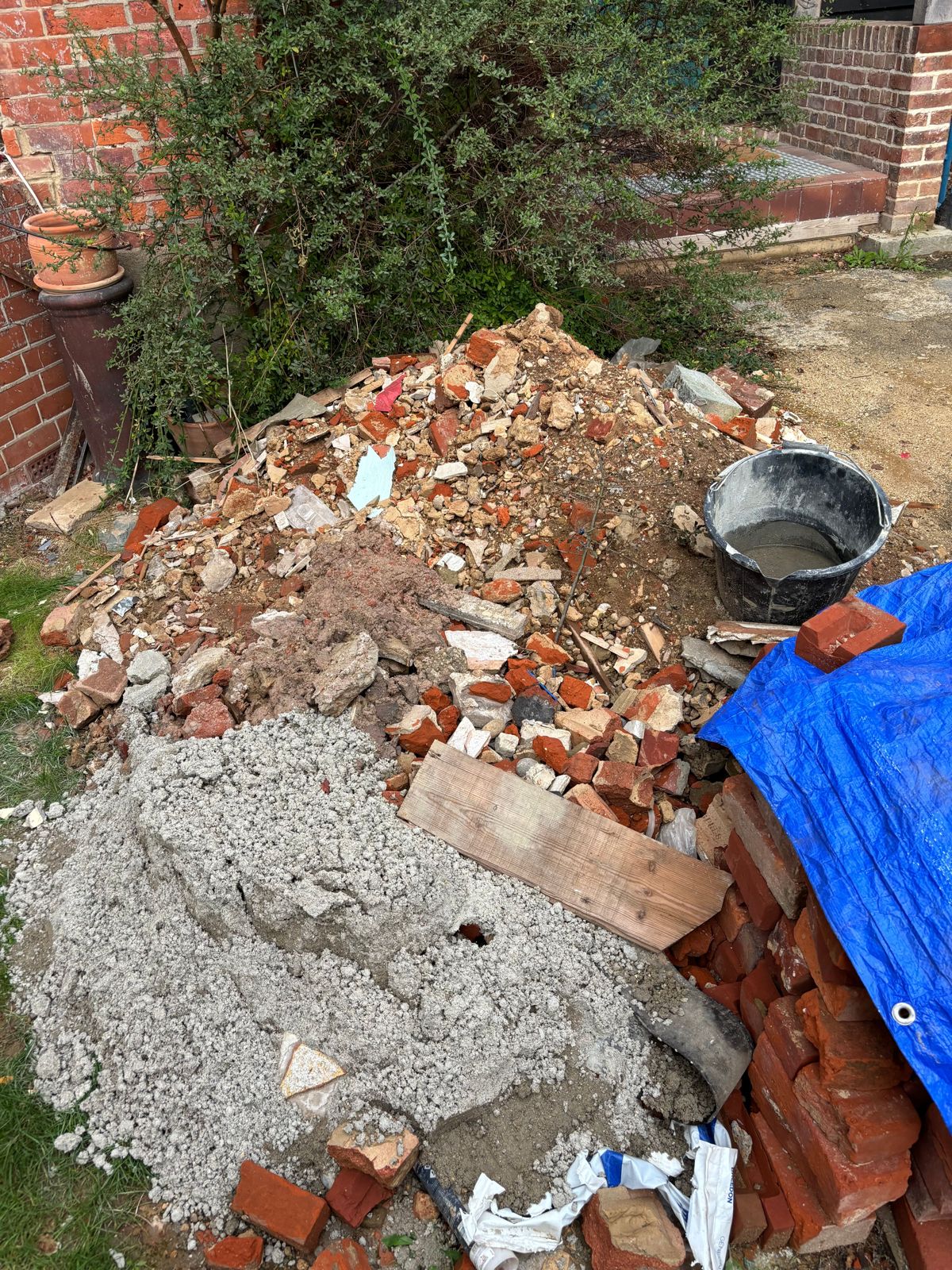 A pile of bricks, rubble and soil beside a house after a strip-out.