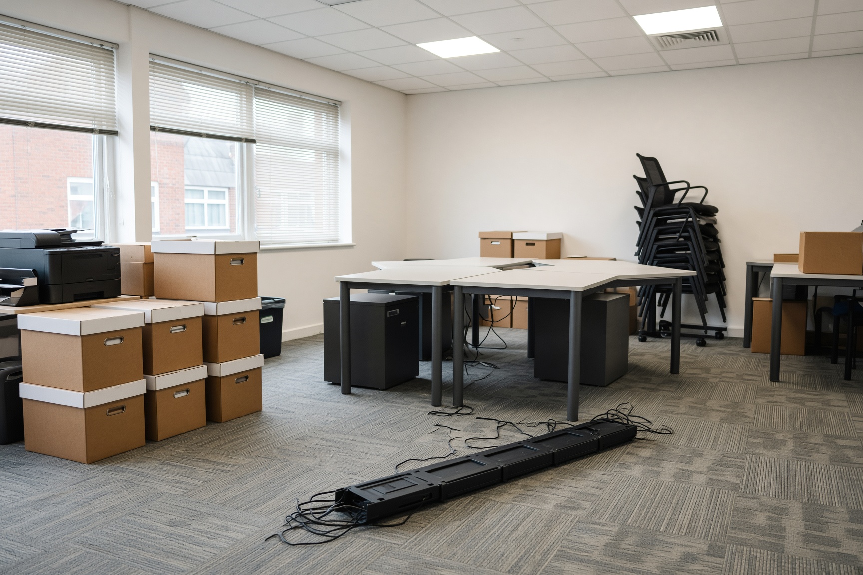 A small office with desks and chairs stacked during a clearance.